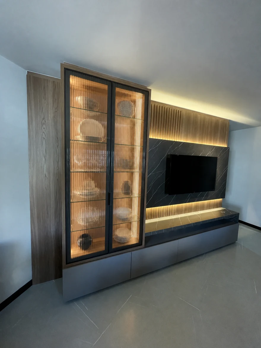 Sala de estar com painel de TV em mármore e cristaleira de vidro canelado iluminada